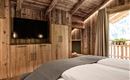 A cozy bedroom with wood paneling and a large television. The large windows provide a view of the outdoors and let in plenty of light.