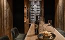 A stylish wine cellar with wooden panels and a long counter. On the counter are a bottle of wine, glasses, and snacks.
