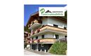 Ein modernes Appartementhaus mit Balkonen und blühenden Blumen. Das Logo "Appartement Panoramablick" ist deutlich sichtbar.
