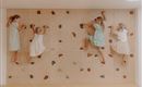 Vier Kinder klettern an einer Kletterwand. Sie tragen verschiedene, sommerliche Kleider und haben viel Spaß.