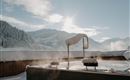A relaxing outdoor pool in a snowy landscape. The sun shines over the mountains, creating a magical atmosphere.
