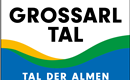 A sign with the inscription "Grossarltal - Valley of the Alps". It displays curved lines in the colors yellow, green, and blue.