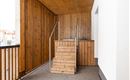 A bright entrance area with a wooden staircase. The walls are adorned with wooden paneling and white plaster.