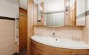A modern bathroom with wood and tile accents. It features a curved sink and large mirrors.