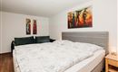 A cozy bedroom with a large double bed and colorful murals. The decor is modern and inviting.