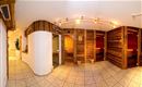 A modern wellness area with wooden paneling and sauna rooms. The space is brightly lit and invites relaxation.