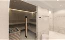 A modern wellness area with a sauna and a shower area. The walls are in neutral tones and there are cozy wooden shelves.