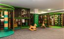 Ein Spielbereich für Kinder mit bunten Kletterstrukturen und einer Rutschbahn. Es gibt auch ein Holzspielzeugpferd zum Spielen.