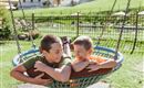 Two happy boys are lying together in a swing seat. They are laughing and enjoying their time outdoors.