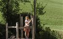 Two children are playing on a playground under a sunshade. In the background, green meadows can be seen.