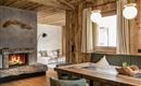 A cozy living space with wooden paneling and a modern fireplace. Large windows provide plenty of light and an inviting view outside.