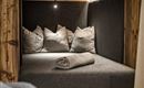 A cozy seating area with dark gray upholstery and several cushions. The wood and soft lighting create a warm atmosphere.