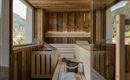 A modern wooden sauna with plenty of natural light. The beautiful mountain landscape can be seen through the windows.