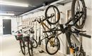 A bike room with several hanging bicycles on the wall. The environment is bright and designed in a modern style.