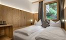 Ein gemütliches Schlafzimmer mit einem Doppelbett und einem großen Fenster. Die Wände sind aus Holz, und die Dekoration ist modern und einladend.