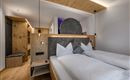 Ein modernes Schlafzimmer mit einem Doppelbett und Holzverkleidungen. Die gemütliche Atmosphäre wird durch sanfte Beleuchtung und stilvolle Dekorationen unterstrichen.