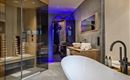 Ein modernes Badezimmer mit einer freistehenden Badewanne und großzügiger Dusche. Die Beleuchtung sorgt für eine entspannende Atmosphäre.