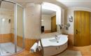 A modern bathroom with a shower and a sink. The walls are light tiled and there is a large mirror.