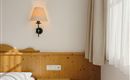 A cozy room with a wooden bed and a soft light source. The room is bright and friendly, with a window and a curtain.